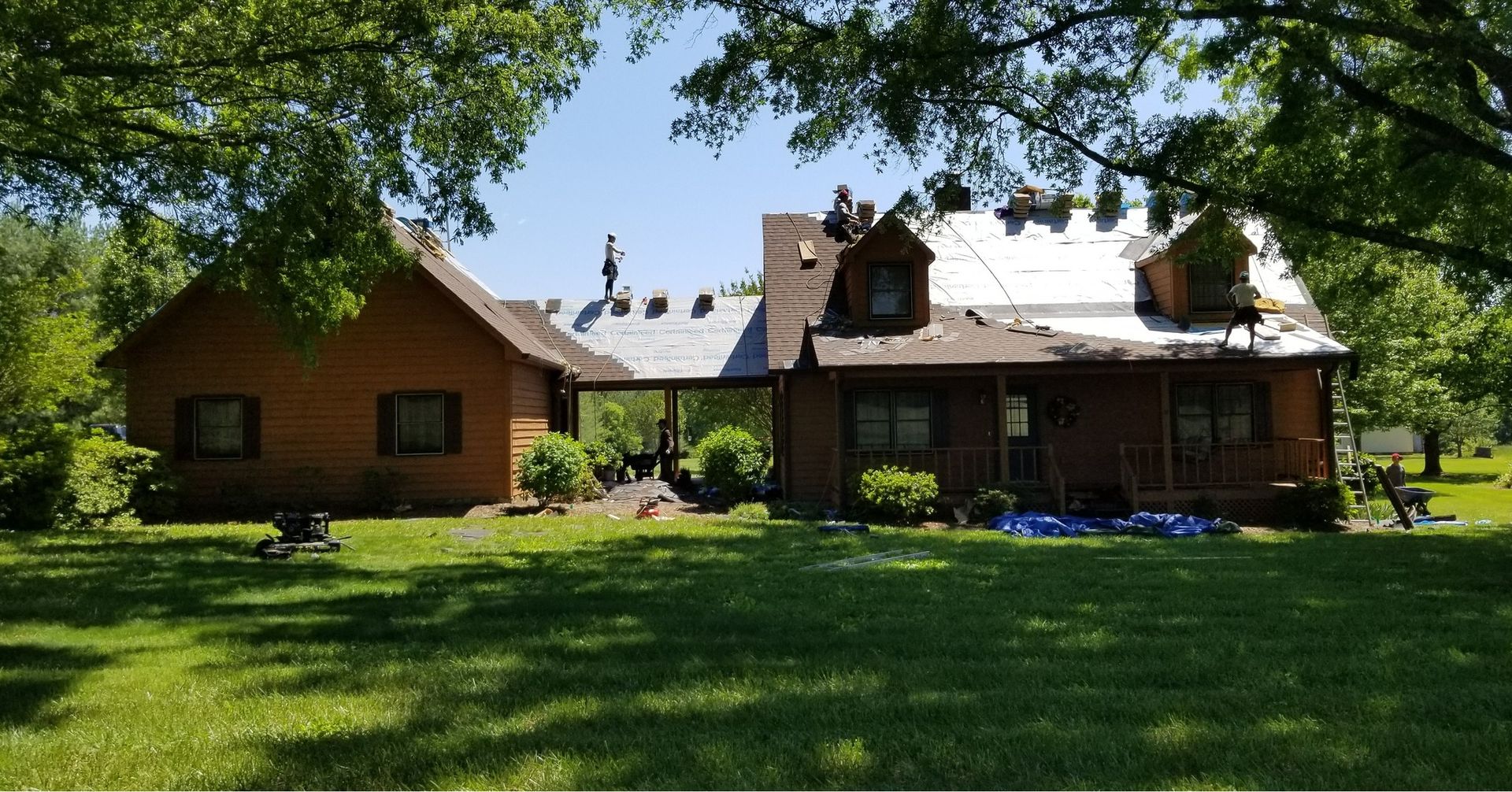 A large house with a porch and a roof that is being remodeled.