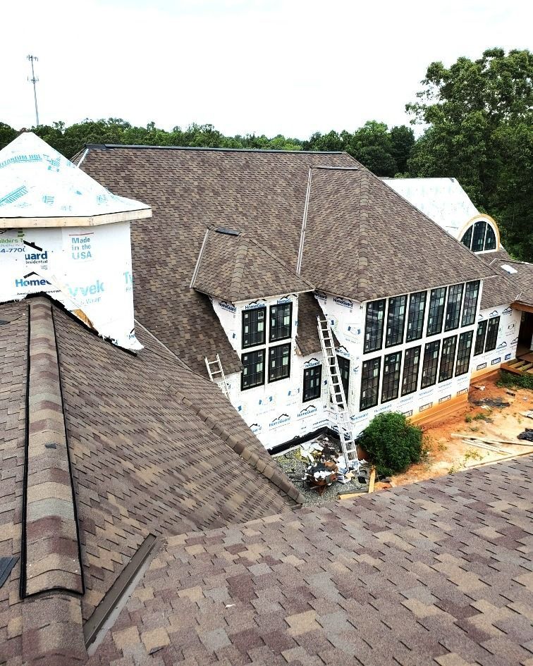 An aerial view of a house under construction with a roof that is being installed.