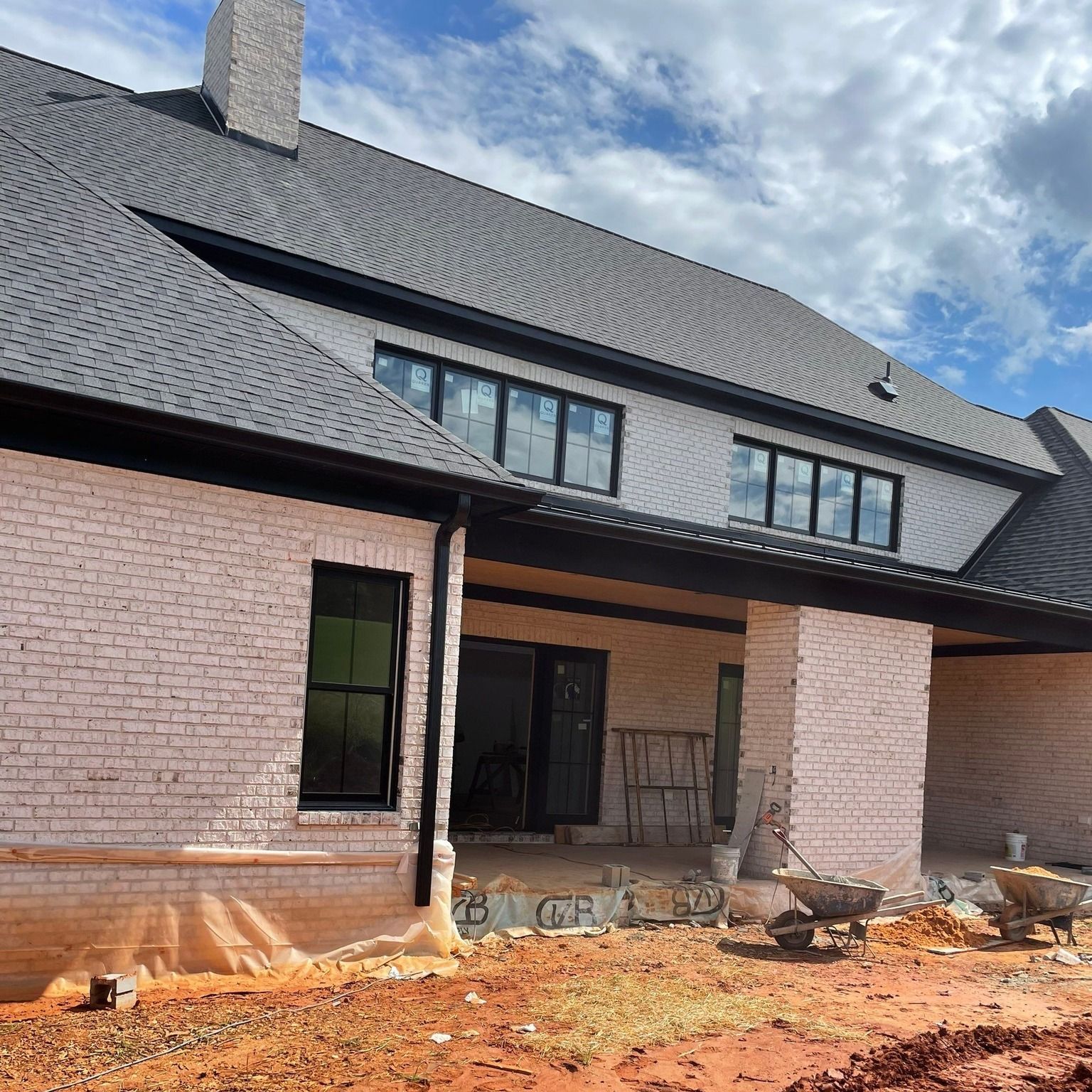 A large white brick house with a gray roof is being built