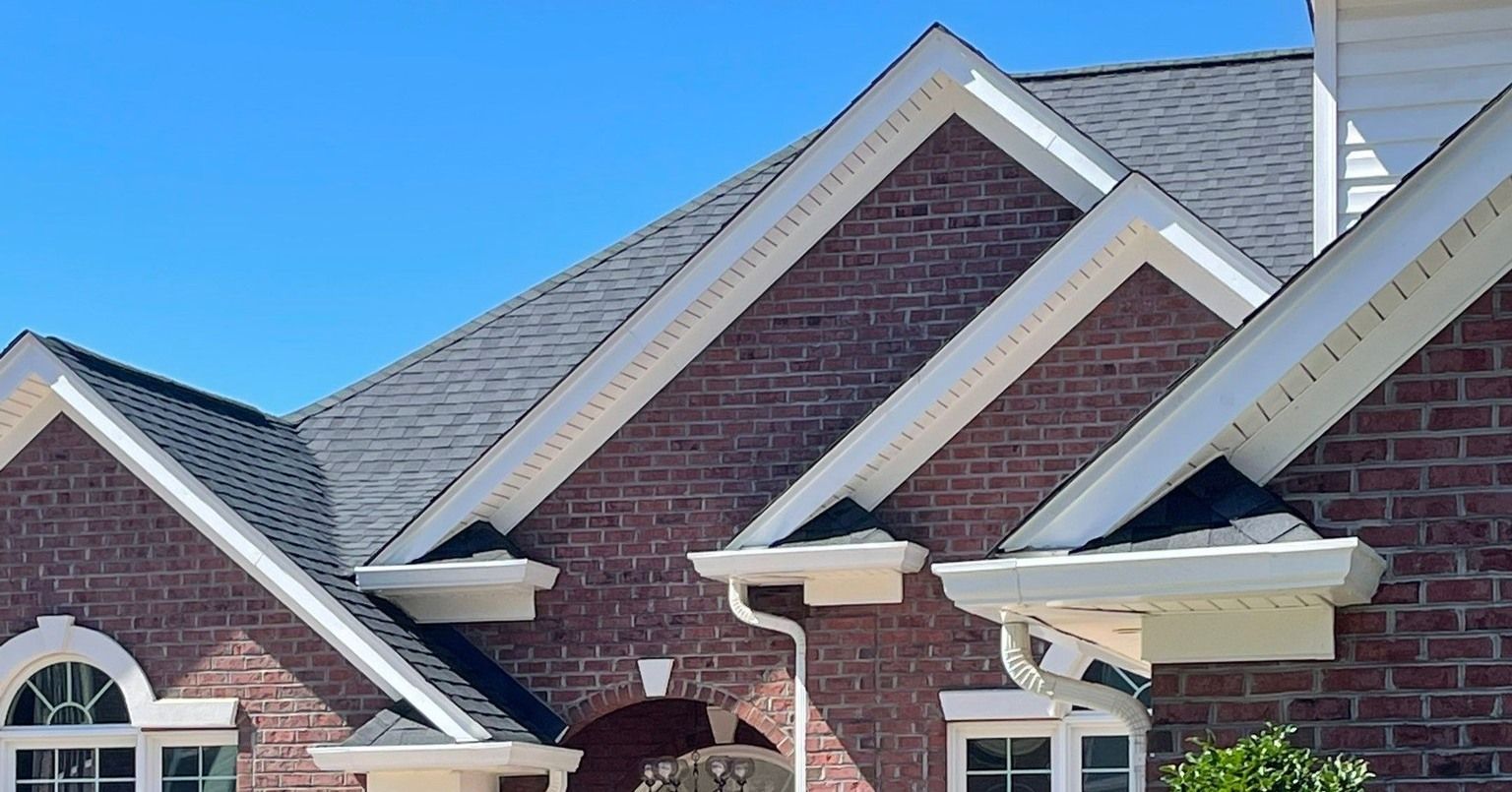 A brick house with a gray roof and white trim