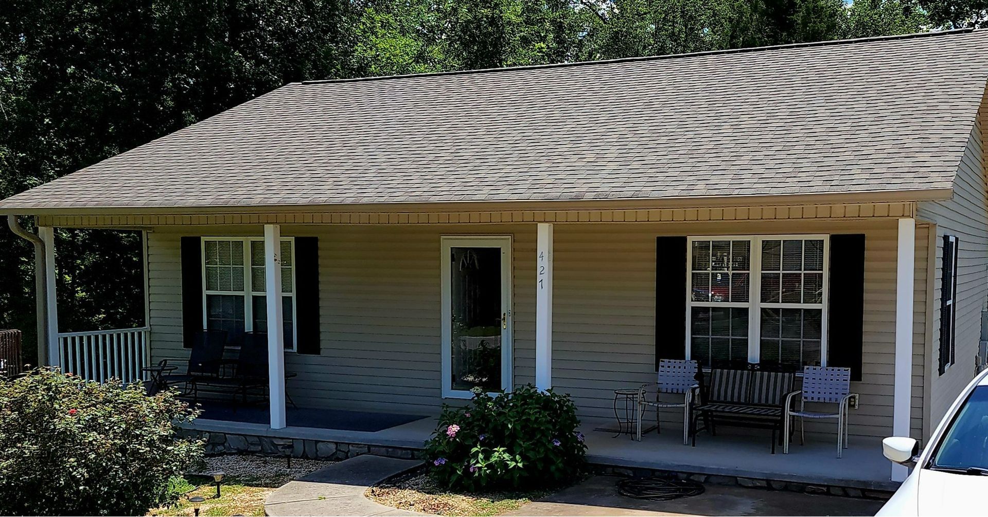 A house with a porch and a car parked in front of it