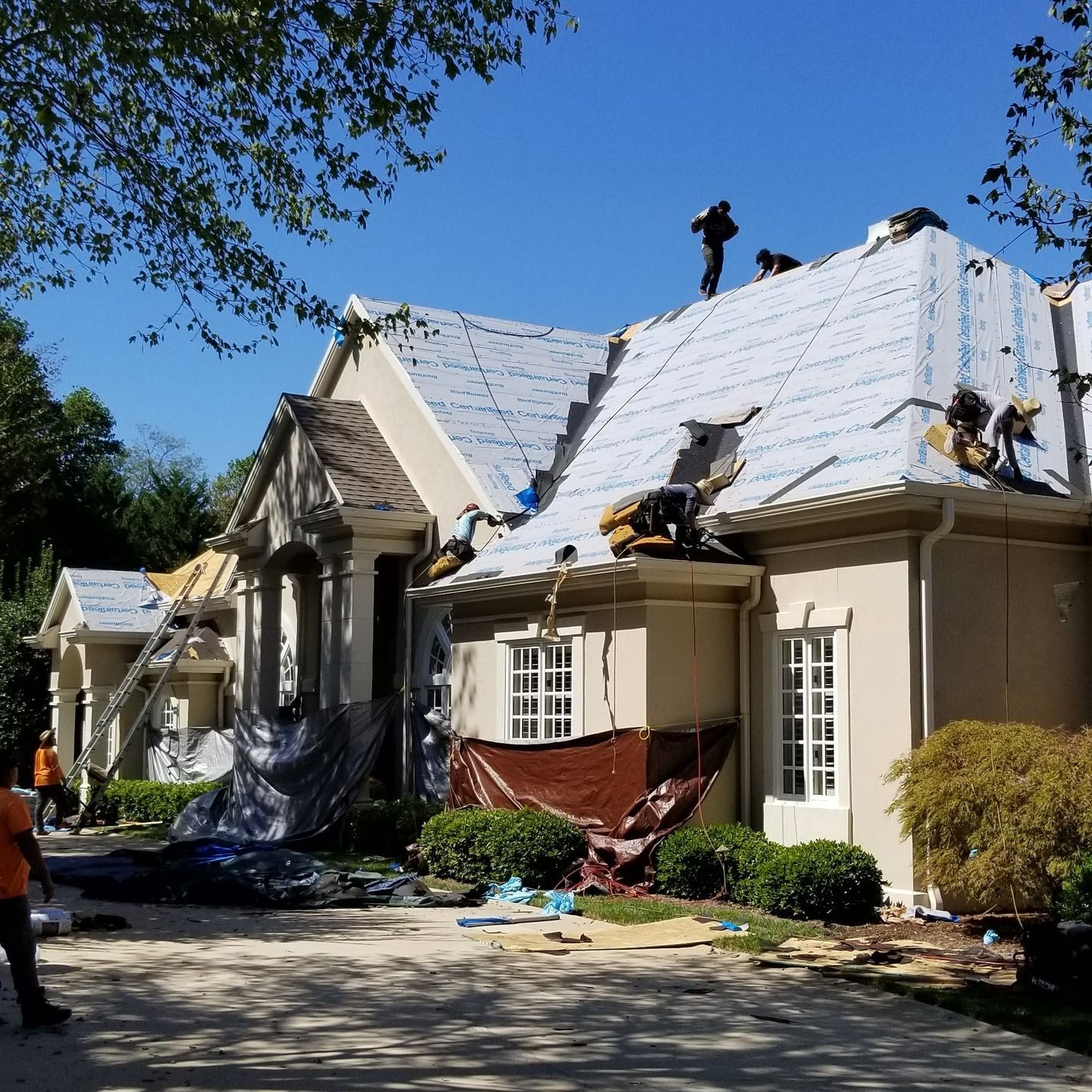 A group of people are working on the roof of a house.