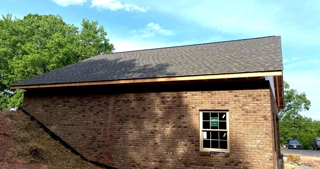 A brick building with a window and a roof is being built.