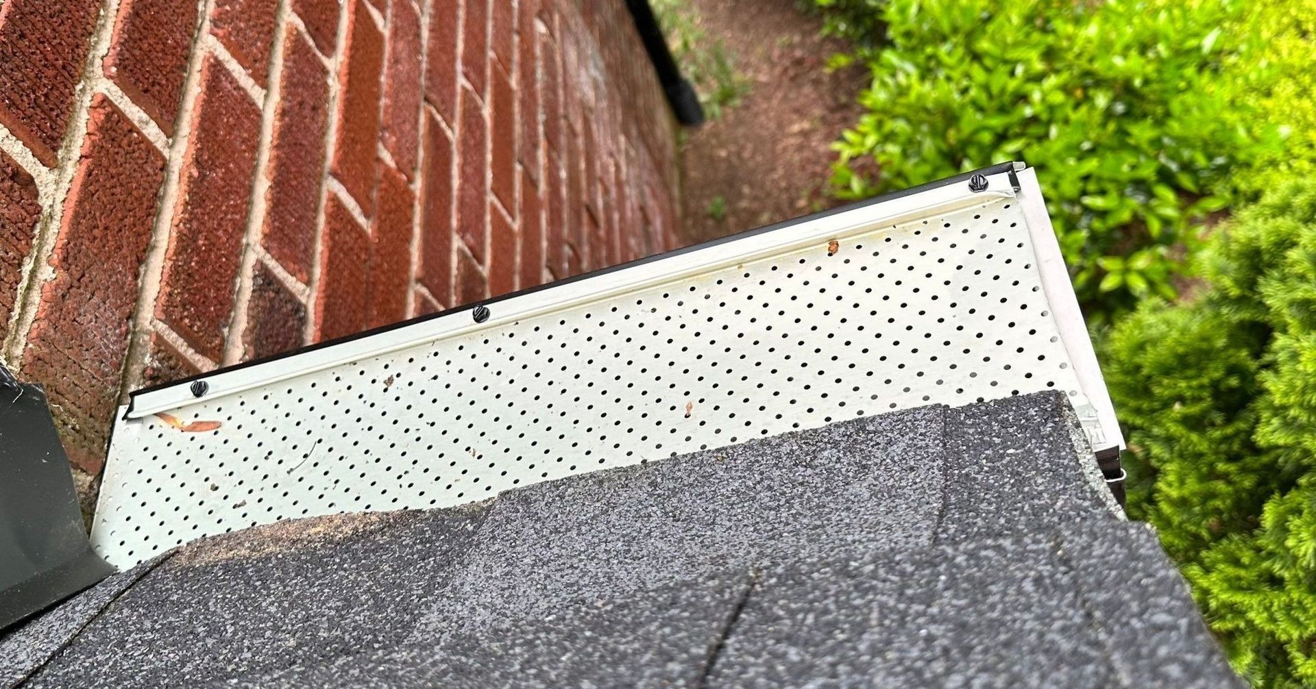 A roof with a drain on it next to a brick wall.