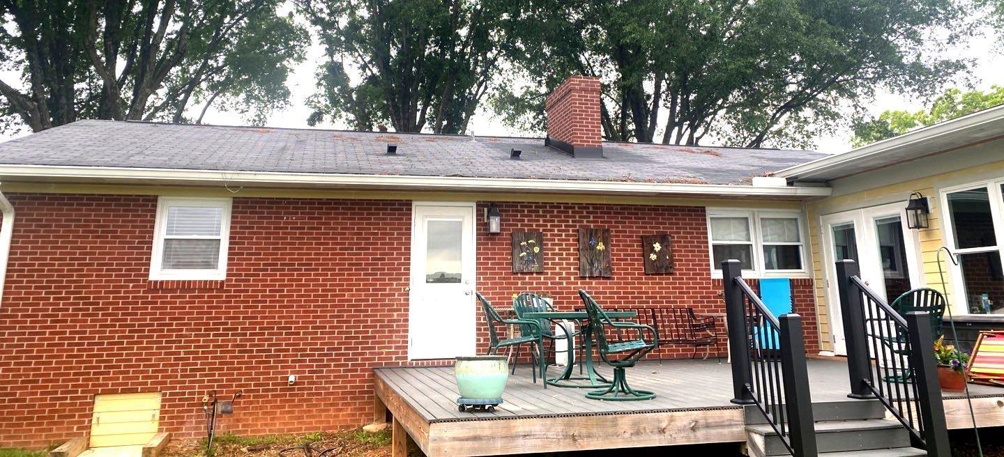 A brick house with a deck and stairs in front of it.