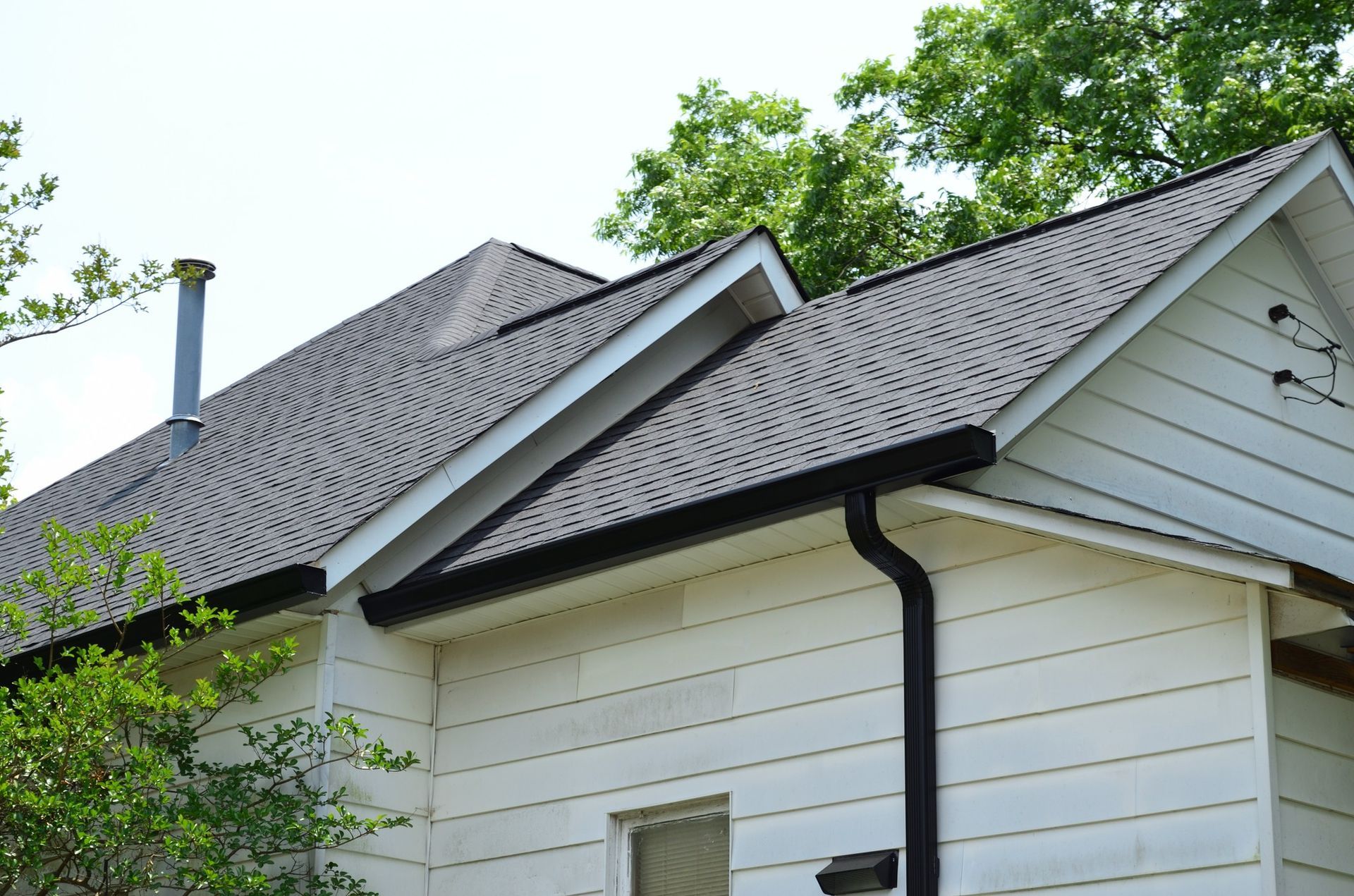 A white house with a gray roof and a black gutter