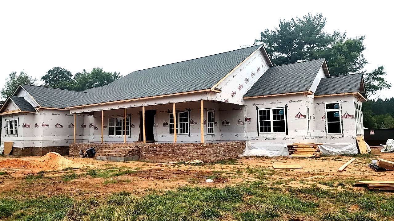 A large house is being built in the middle of a field.