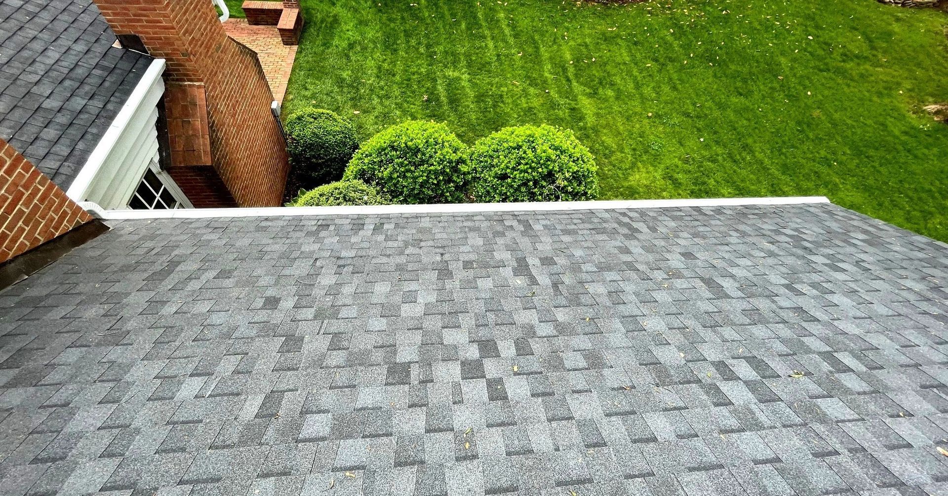 An aerial view of a roof of a house with a lush green lawn in the background.