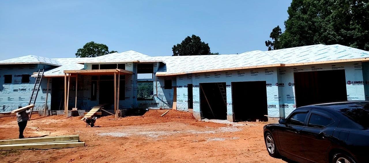 A car is parked in front of a house under construction.