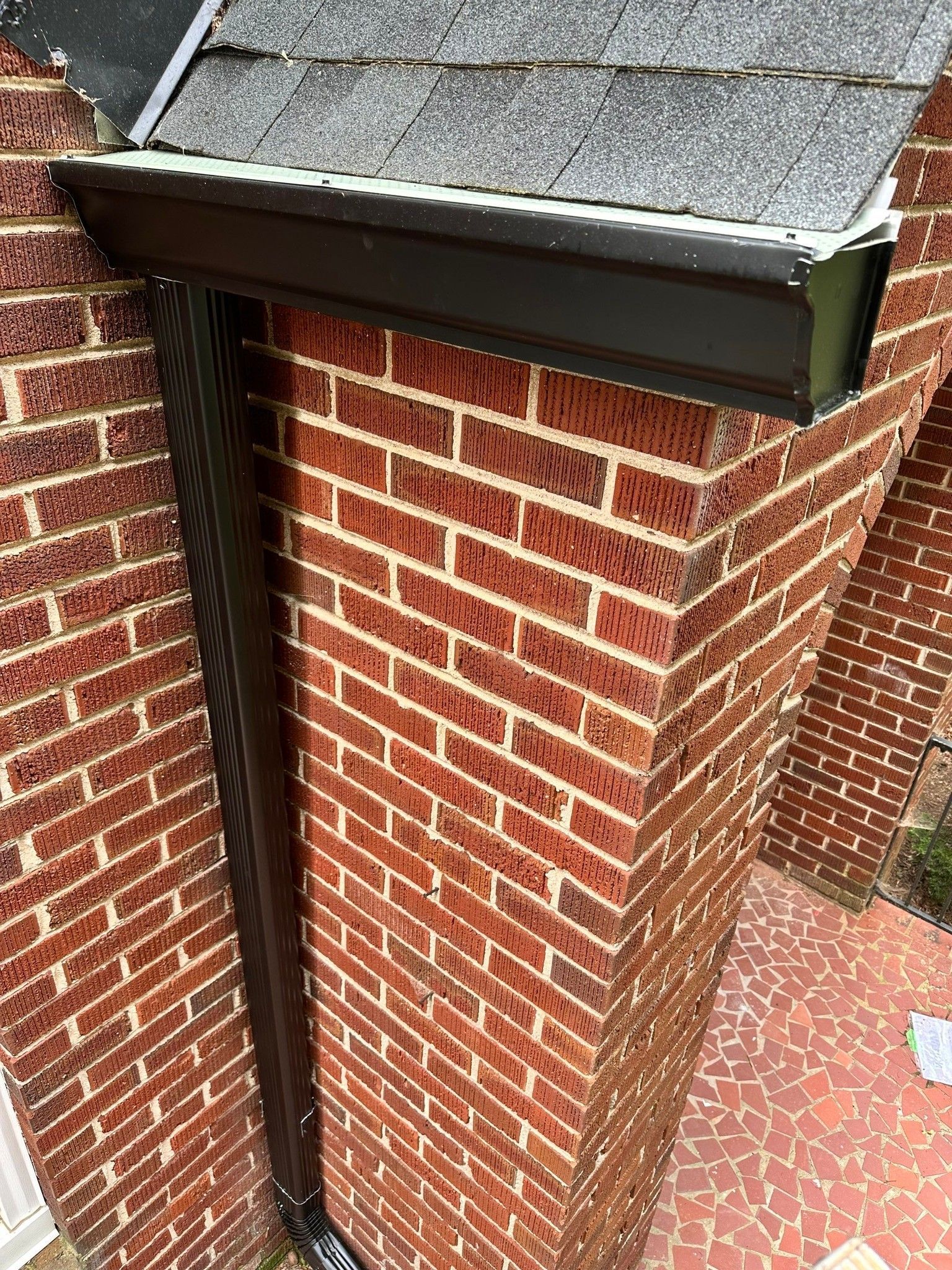A brick building with a black gutter on the side of it.
