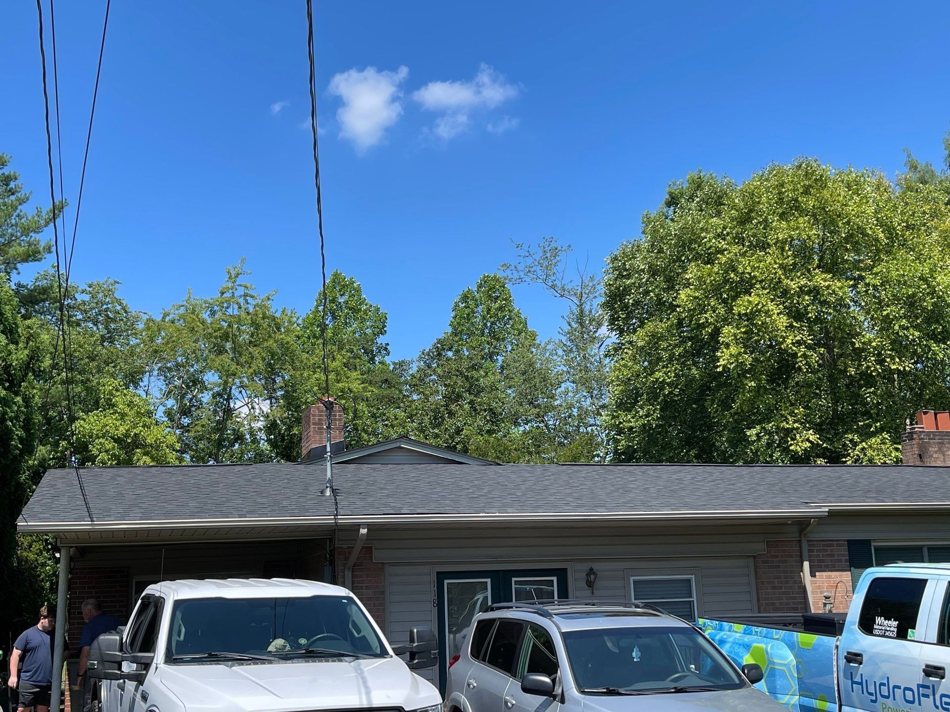 Two cars are parked in front of a house on a sunny day.