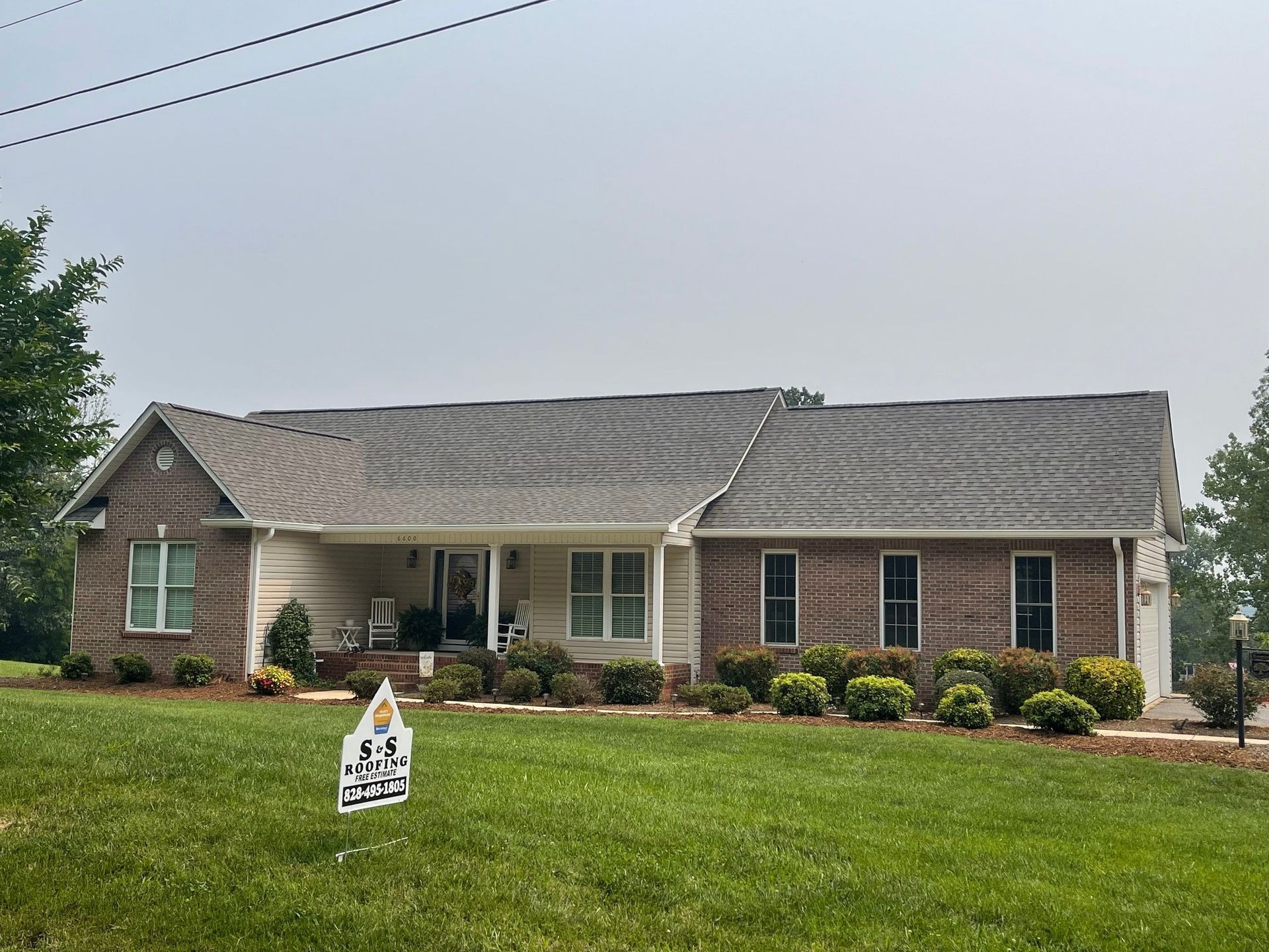 A large brick house with a sign in front of it.