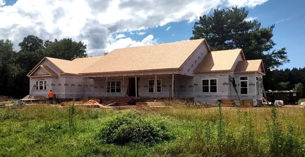 A house is being built in a field with trees in the background