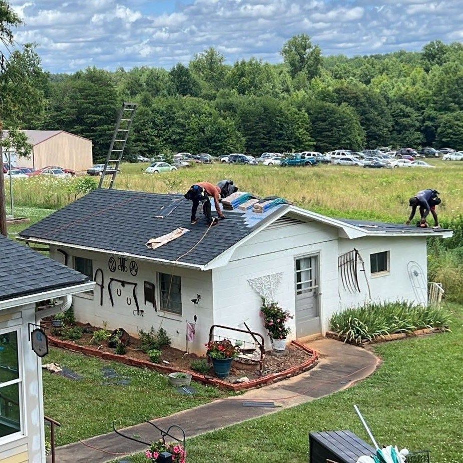 A group of people are working on the roof of a house.