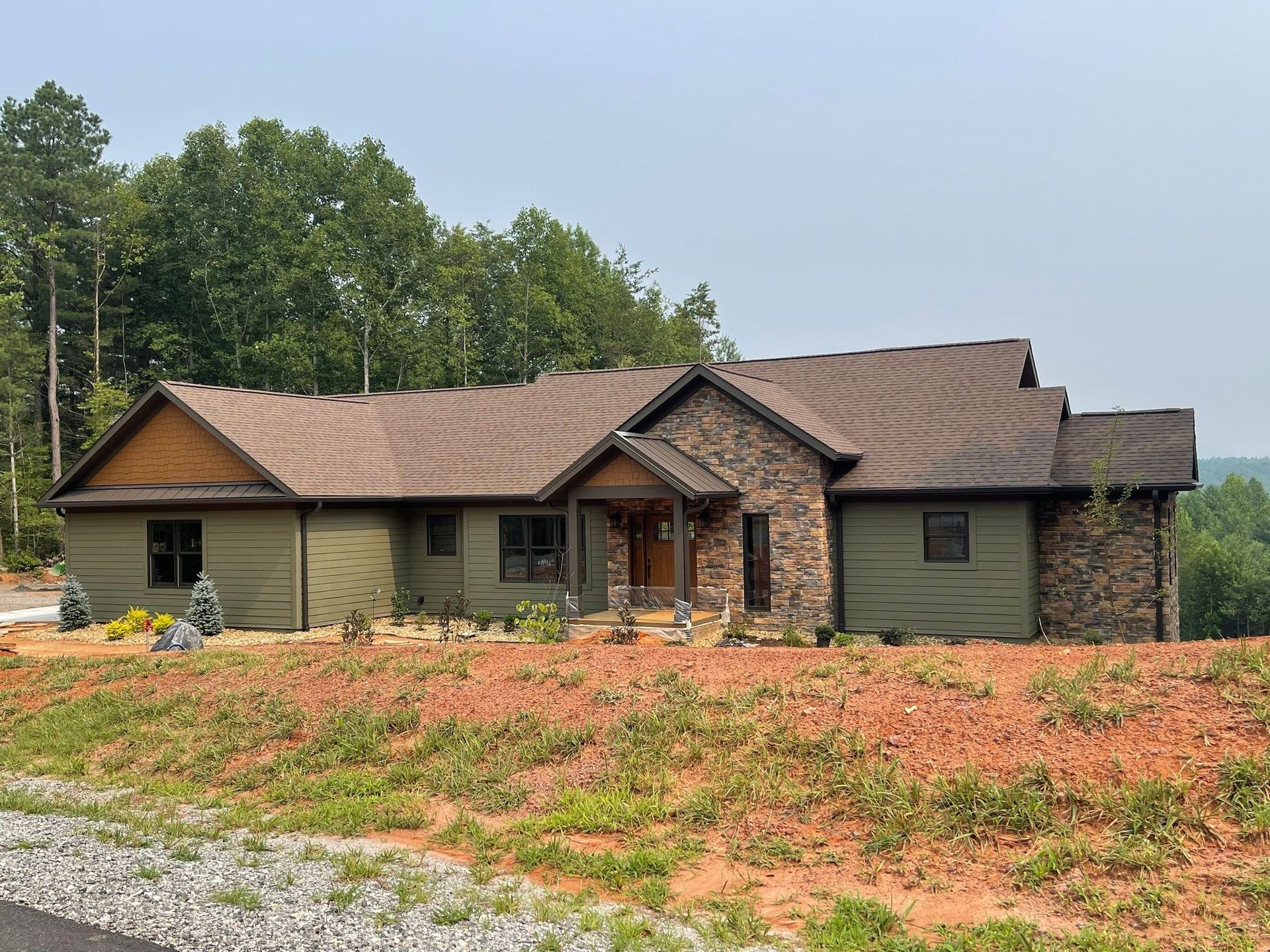 A large house is sitting on top of a hill surrounded by trees.