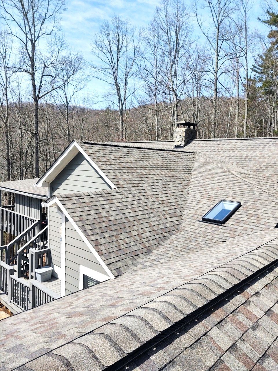 A roof with a skylight on it and trees in the background.