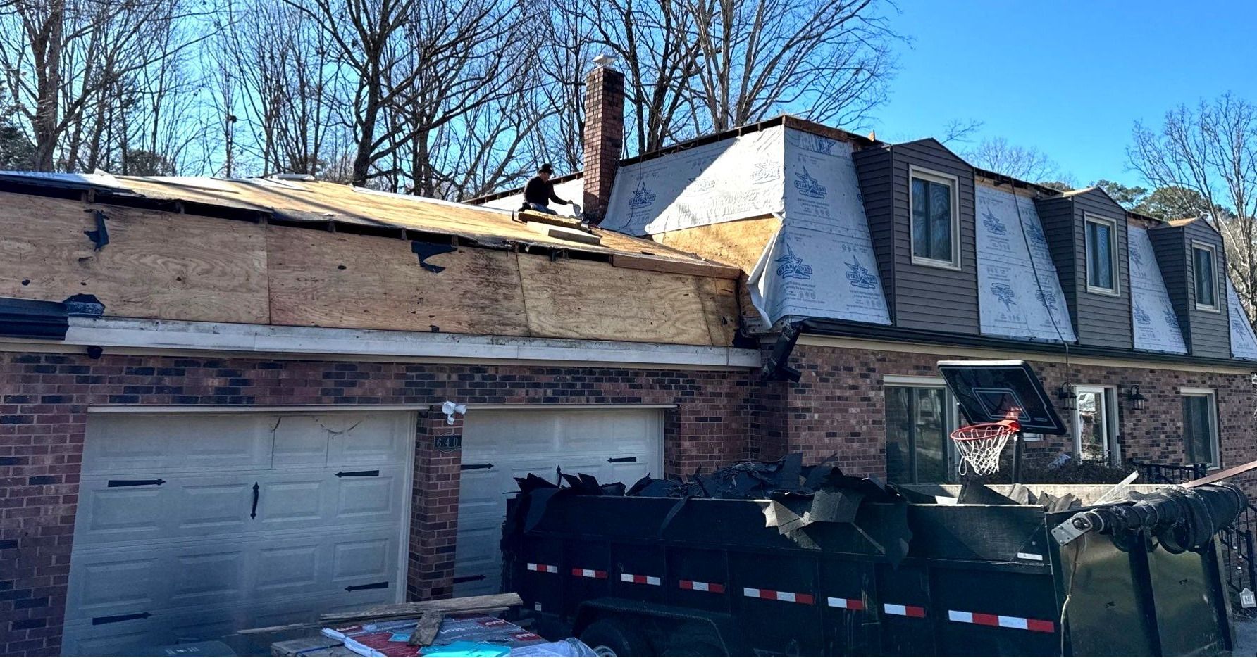 A house is being remodeled with a dumpster in front of it.