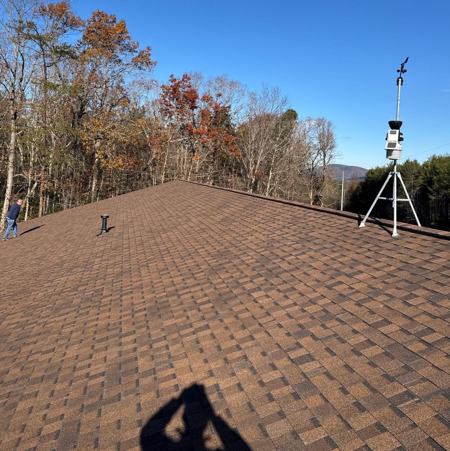 A shadow of a person is cast on the roof of a house