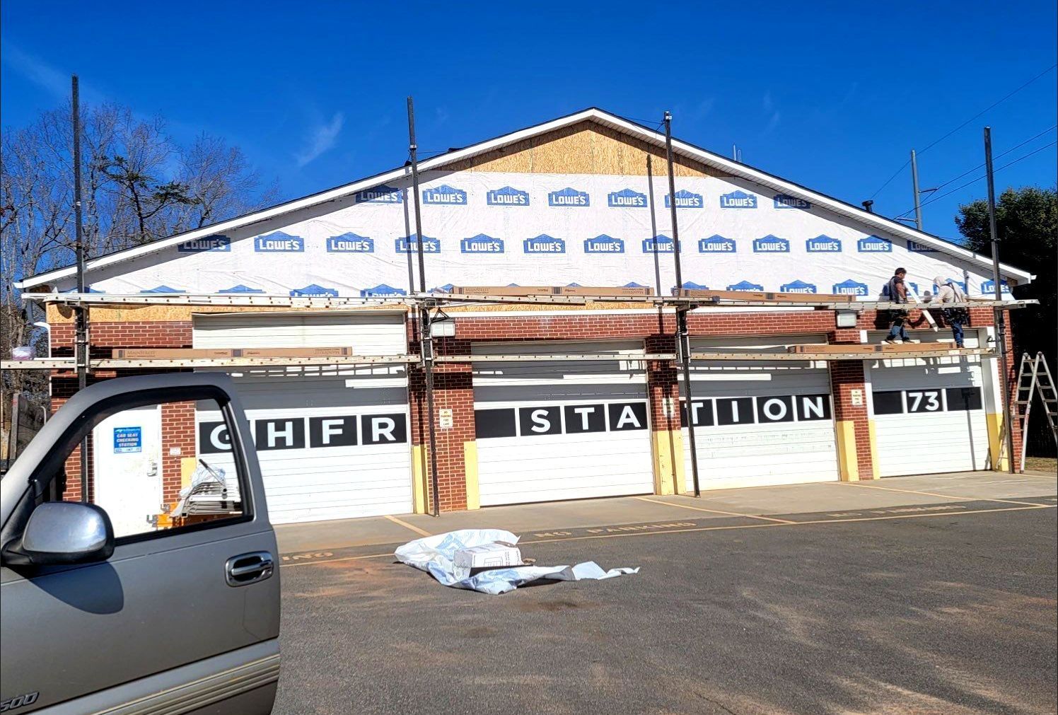 A car is parked in front of a building that is being remodeled.