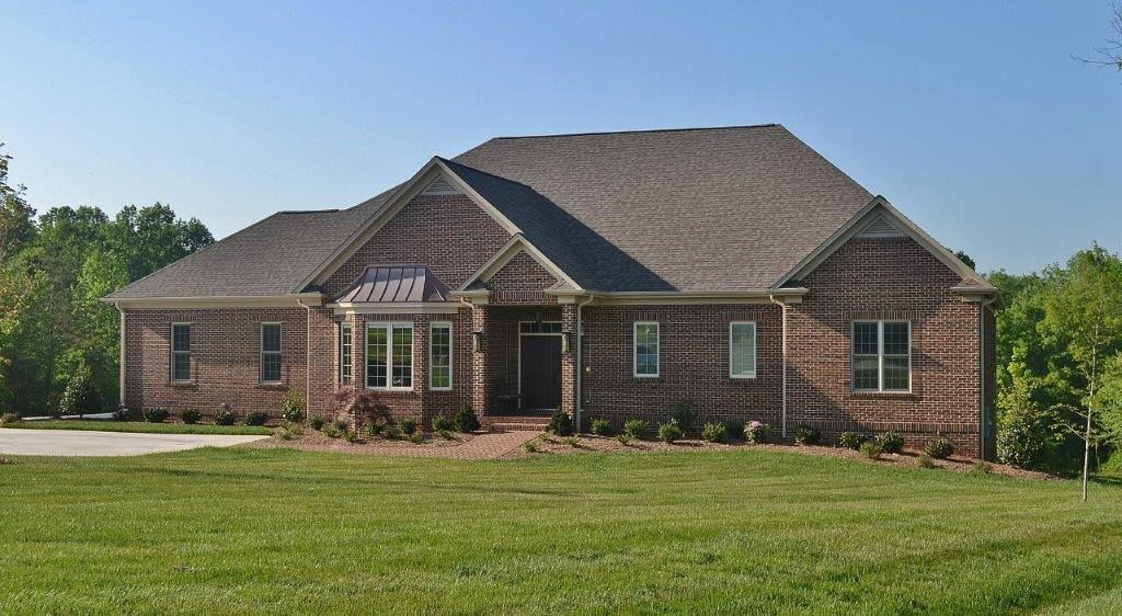 A large brick house sits in the middle of a lush green field.