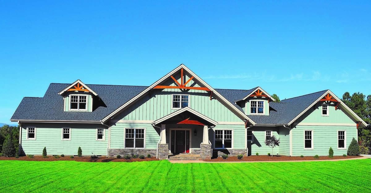 A large house is sitting on top of a lush green field.