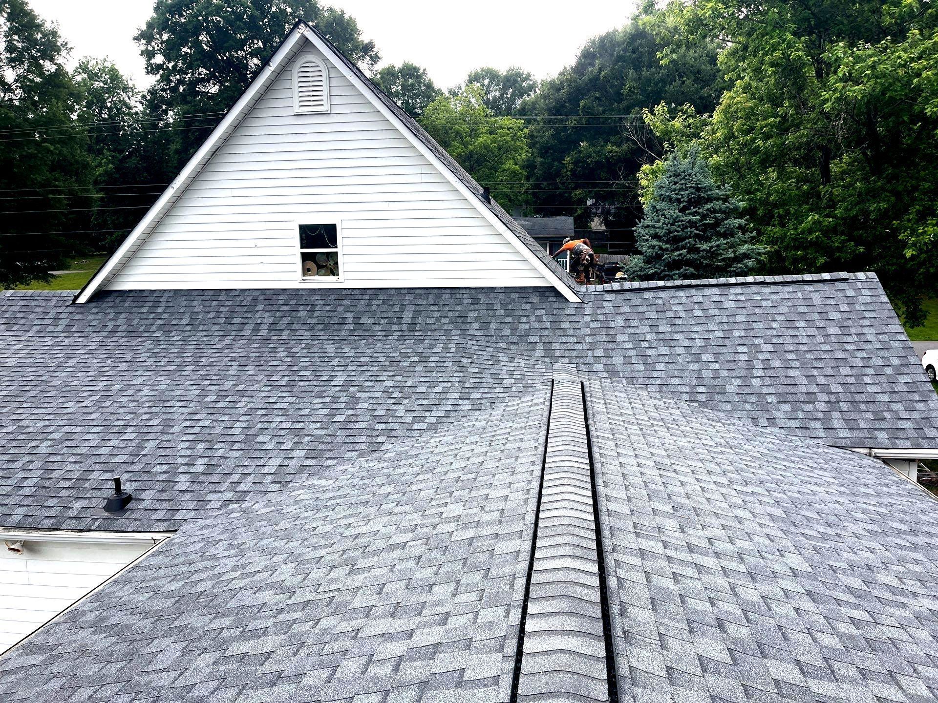 A construction worker wearing a blue hard hat is working on a roof