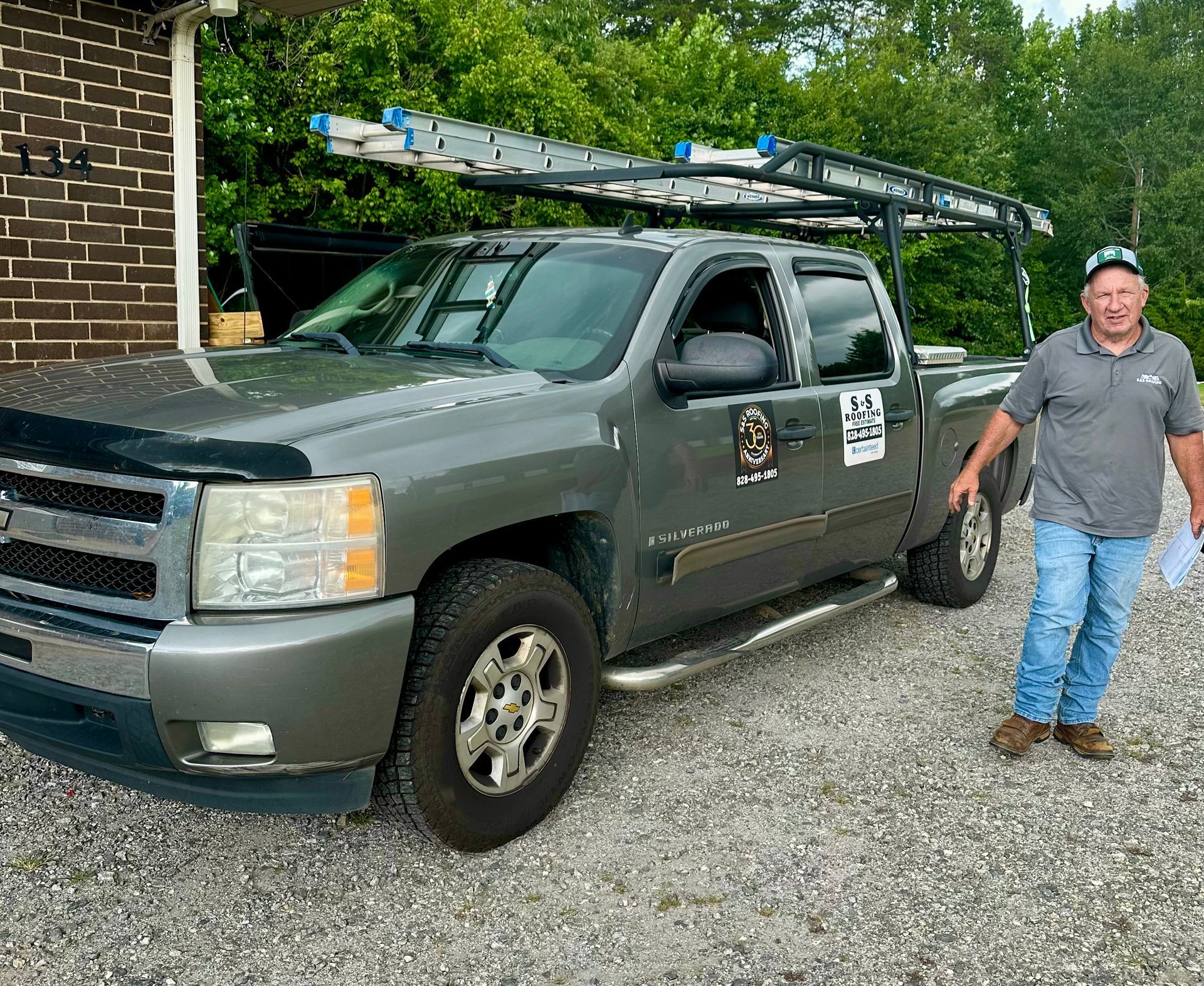 A man is standing next to a truck with a ladder on top of it.