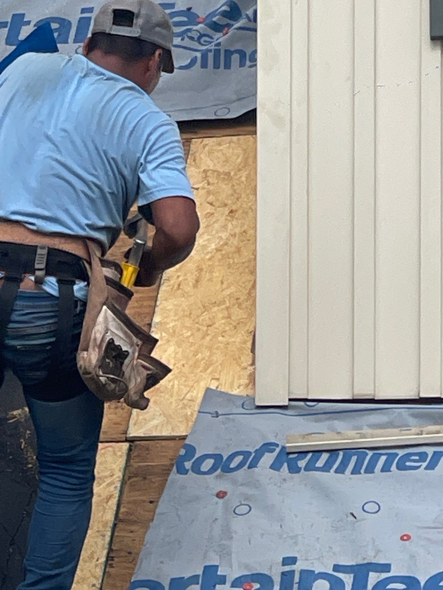 A man in a blue shirt is working on a roof.