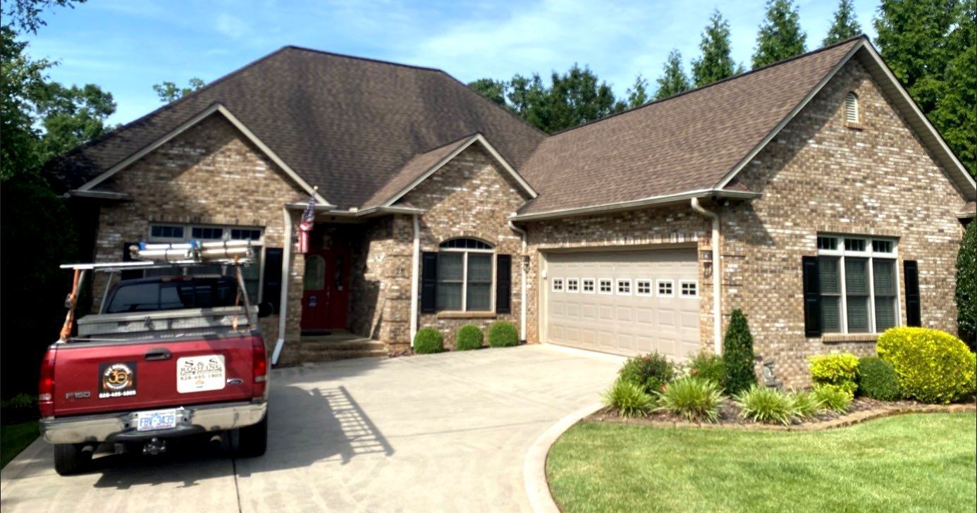 A red truck is parked in front of a large brick house.