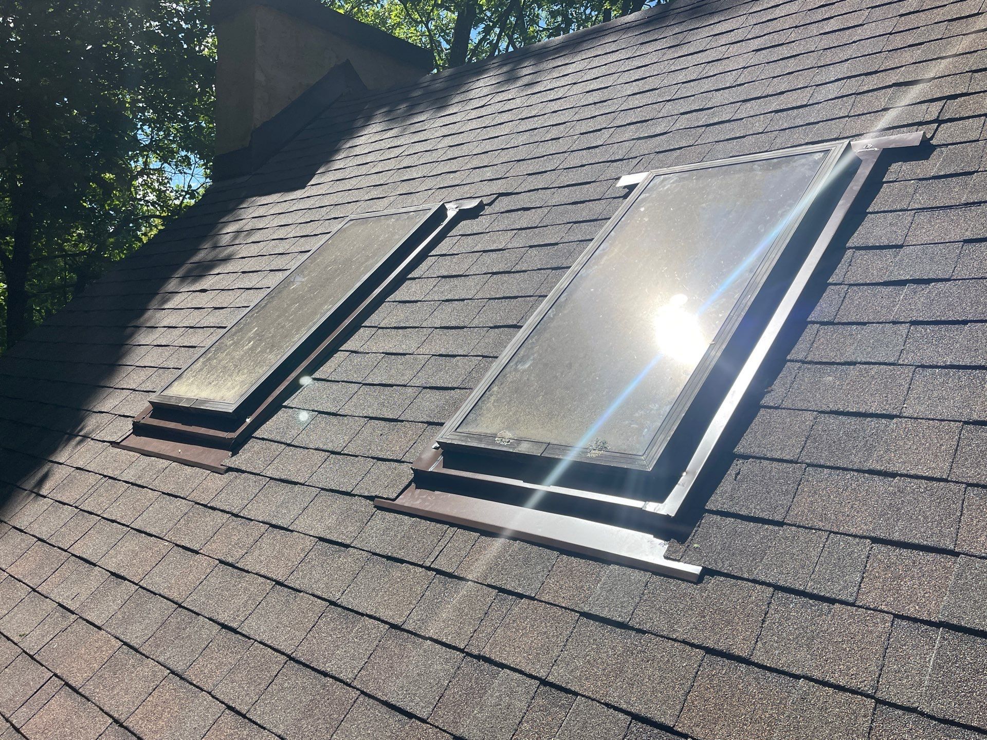 Two skylights on the roof of a house with the sun shining through them