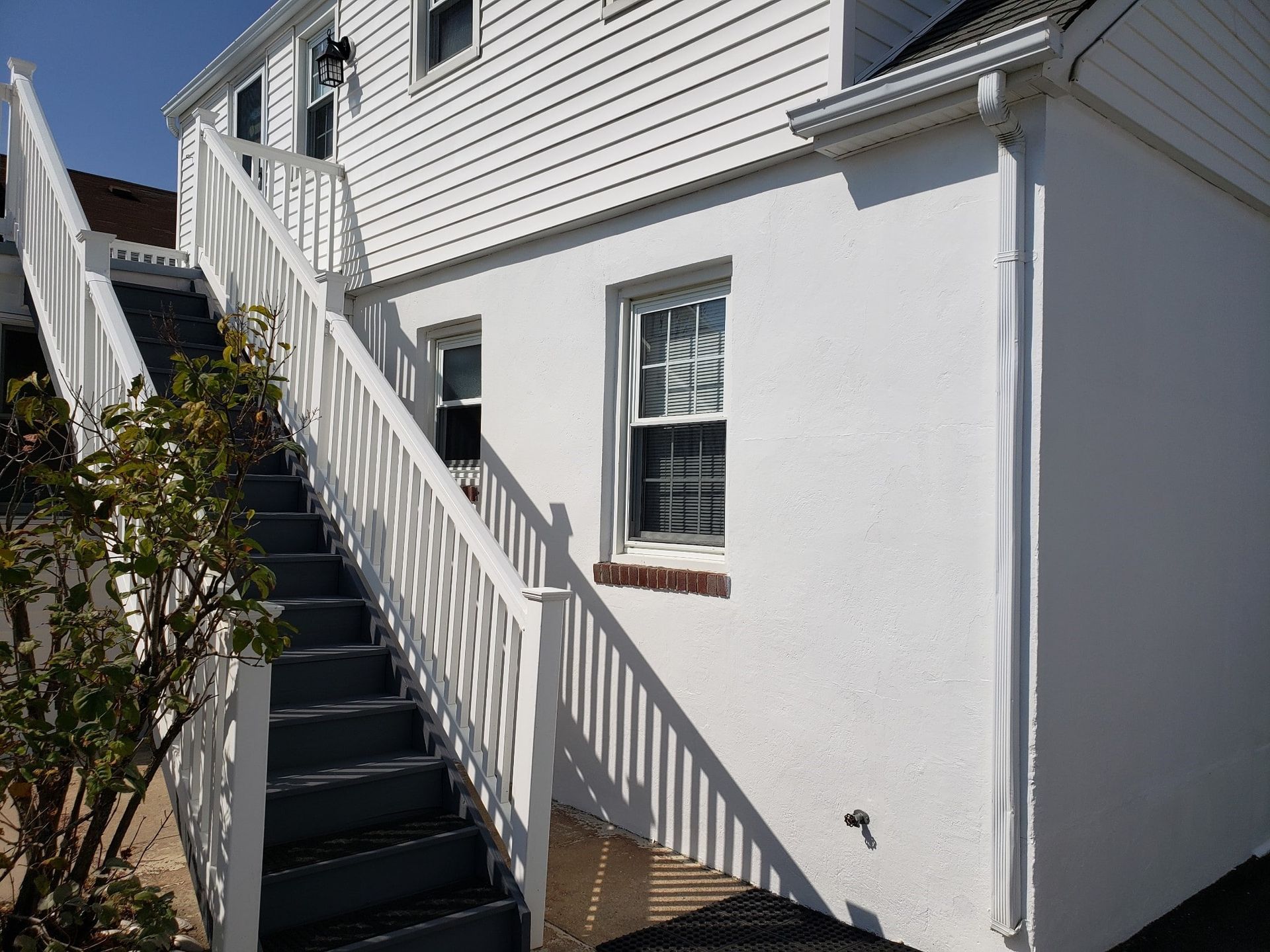 A white house with stairs leading up to the second floor