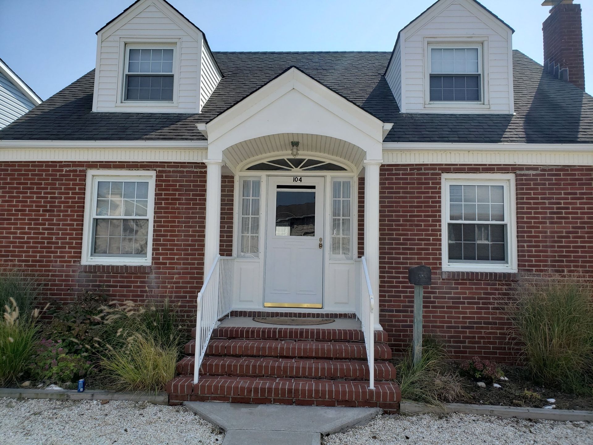 A brick house with a white porch and stairs
