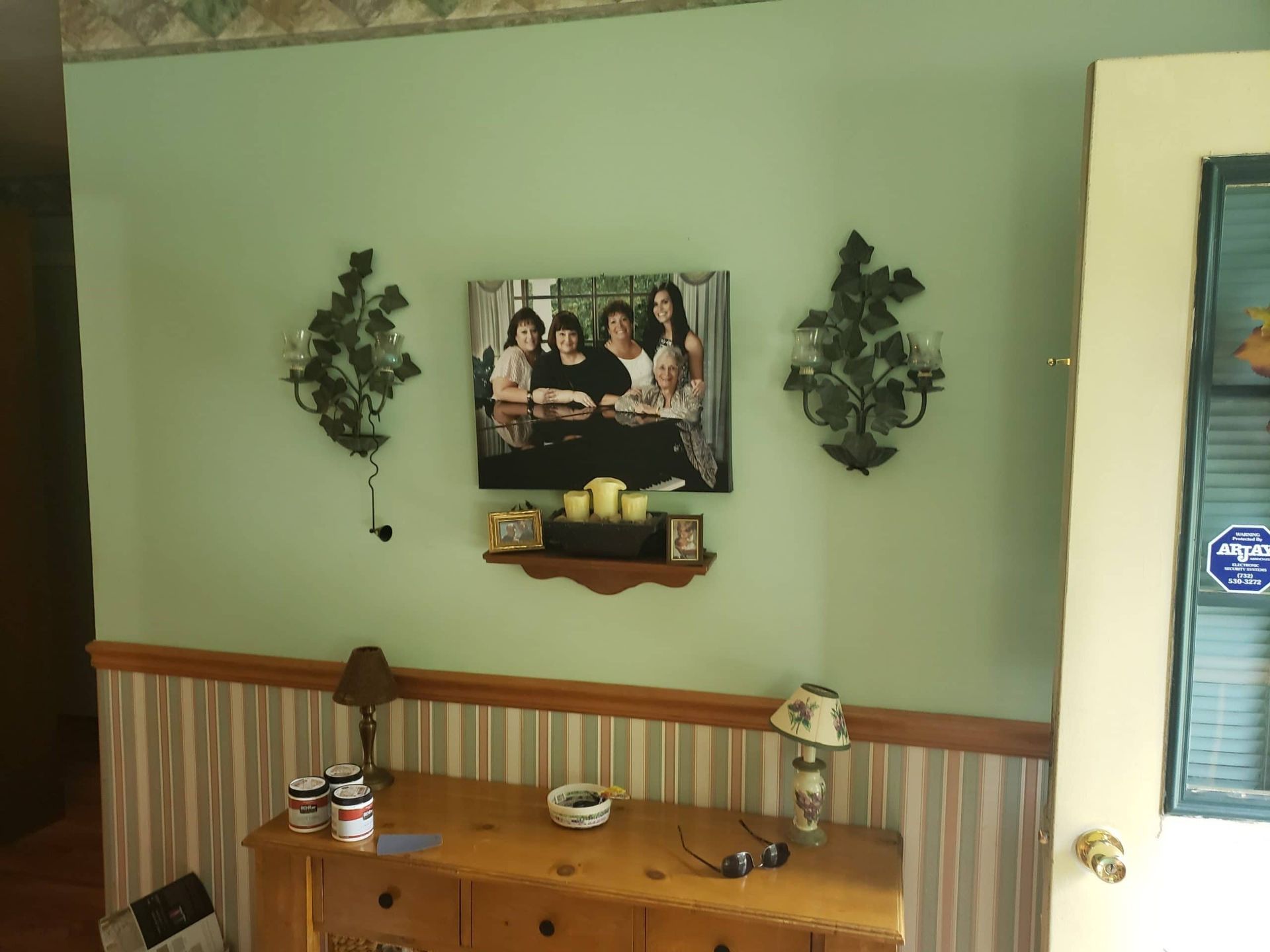 A picture of a group of people is hanging on a wall above a dresser