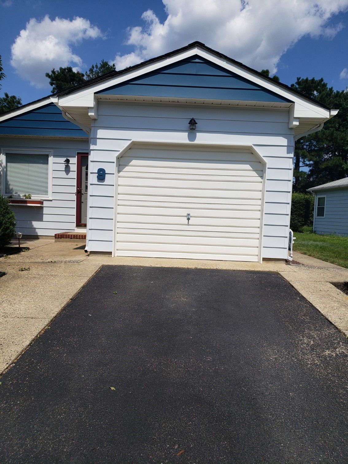 A white house with a blue roof and a black driveway