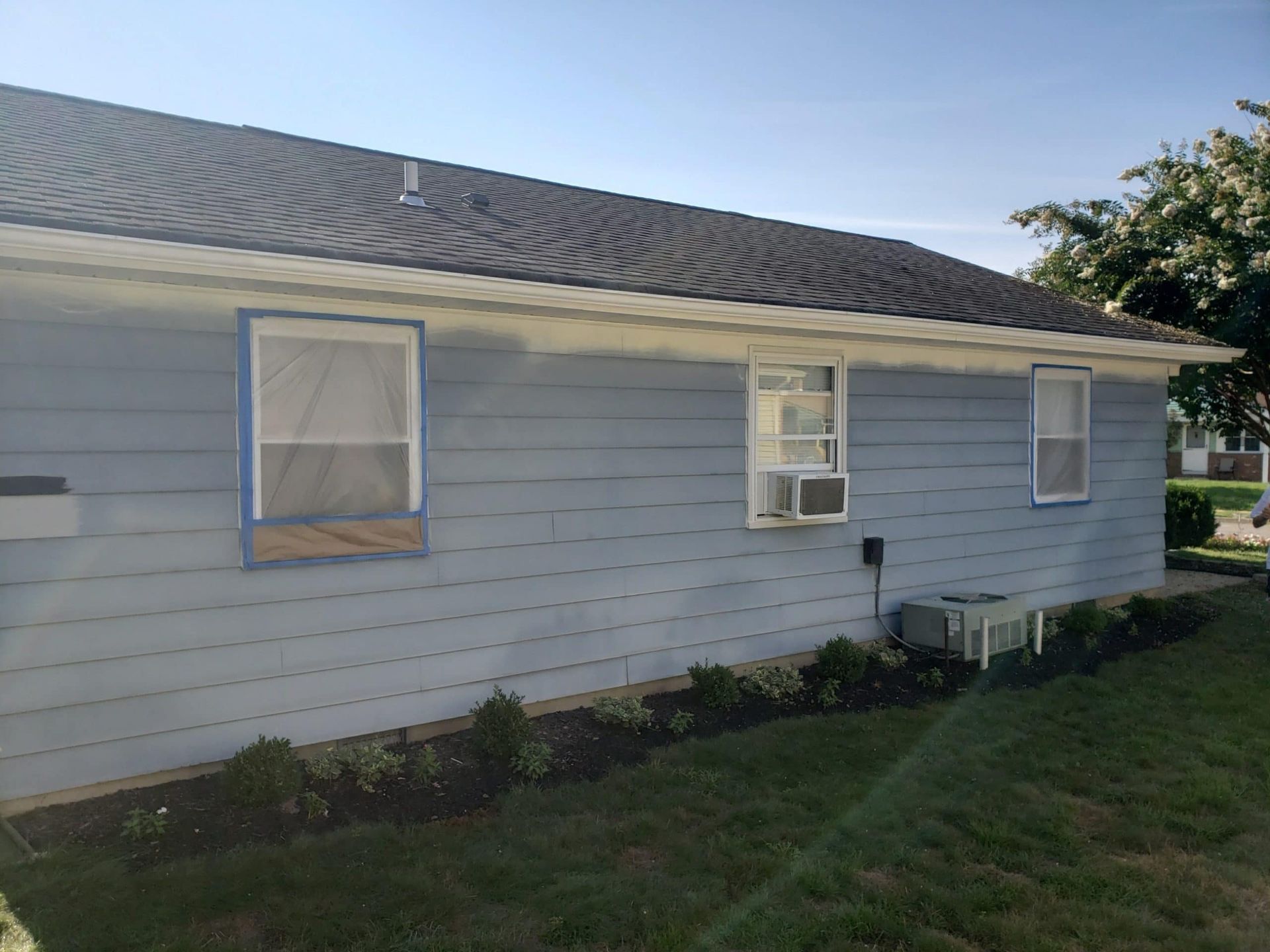 The side of a house is being painted blue and white.