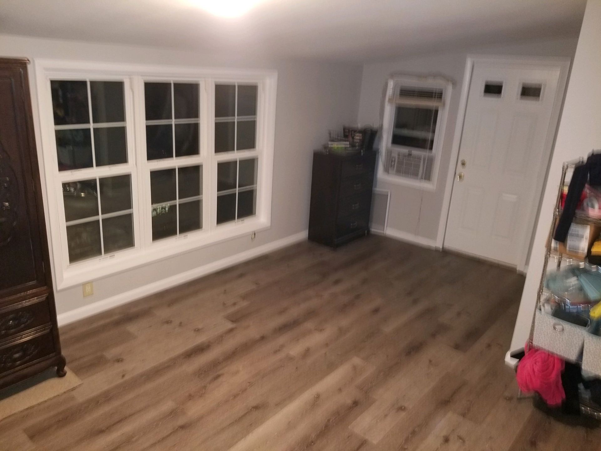 A living room with hardwood floors and a large window