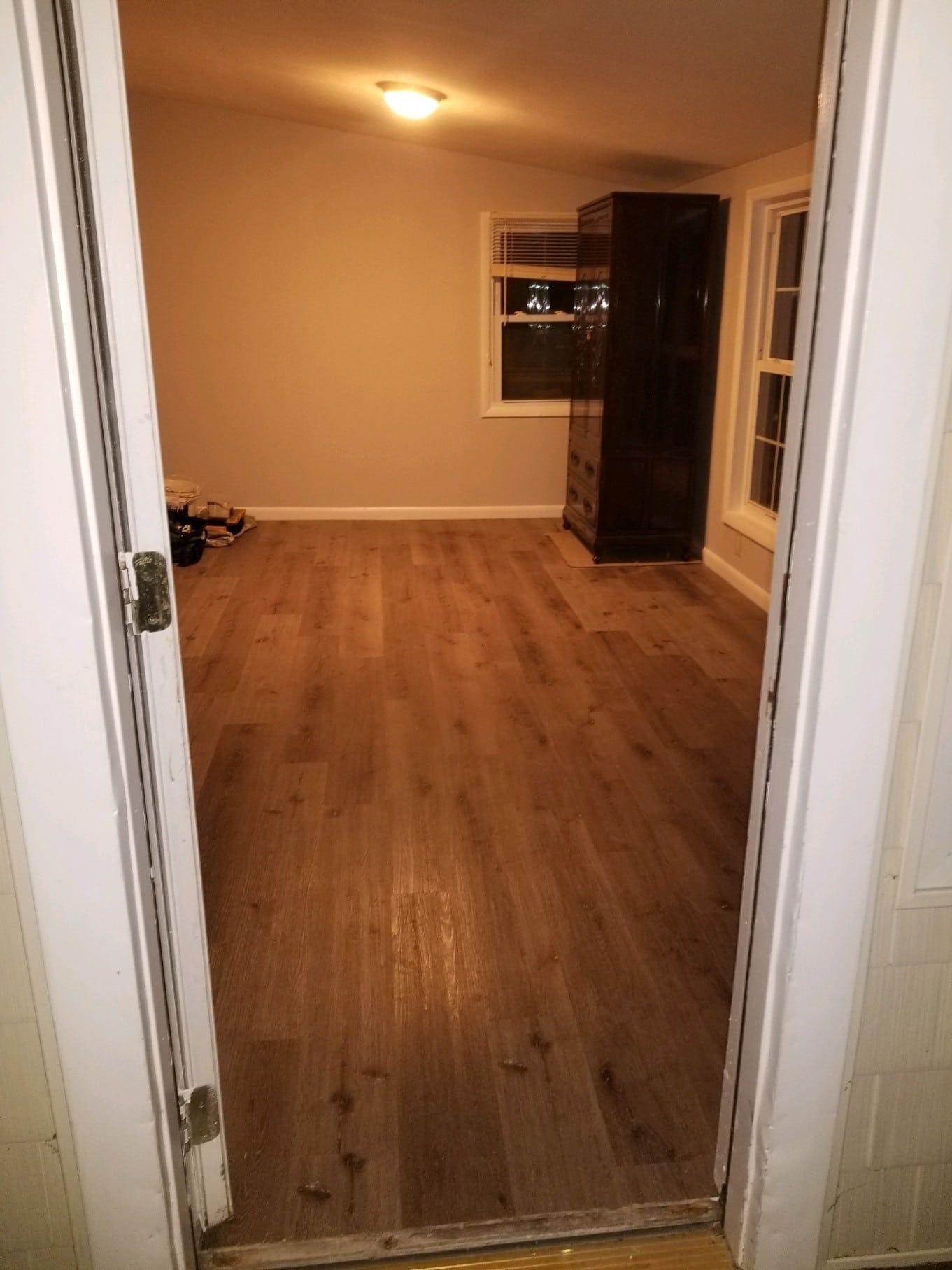 A doorway leading into a room with hardwood floors and a window.