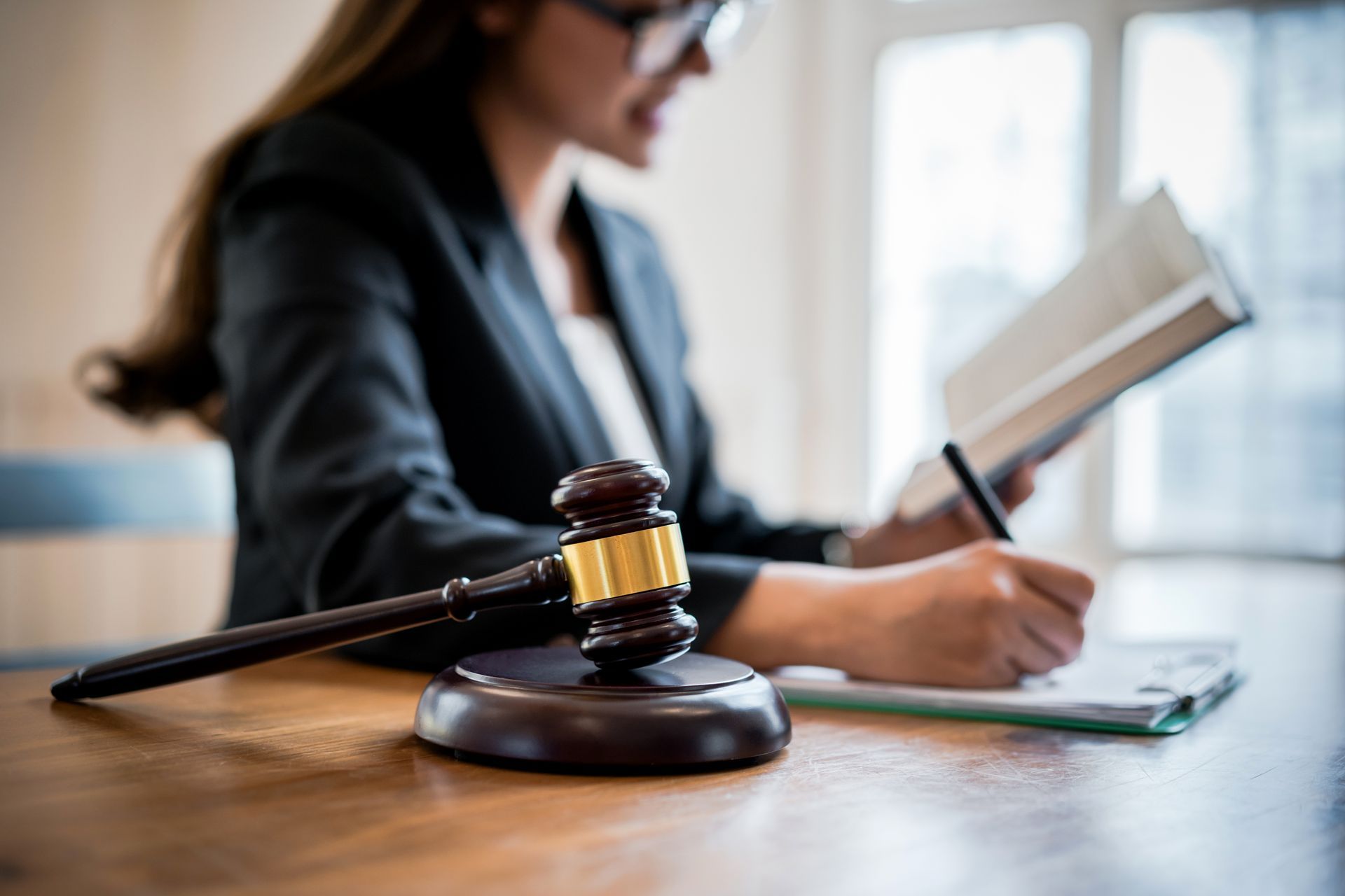 Lawyer focused on employment law, writing at desk with gavel in the foreground. Lawyer focused on employment law, writing at desk with gavel in the foreground.