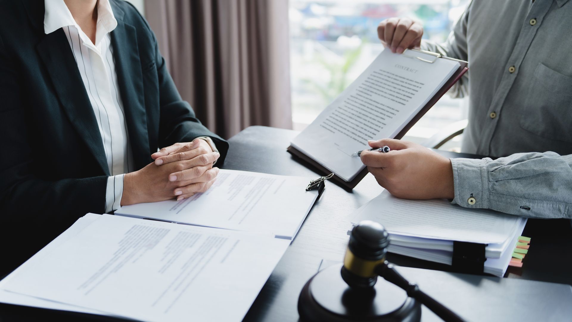 Experienced employment law firm advocate reviewing workplace claim documents with a client. Experienced employment law firm advocate reviewing workplace claim documents with a client.