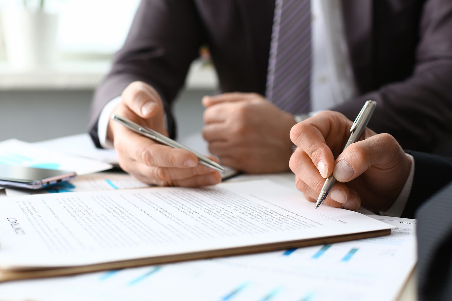 An employment law attorney discussing legal documents with a client. An employment law attorney discussing legal documents with a client.