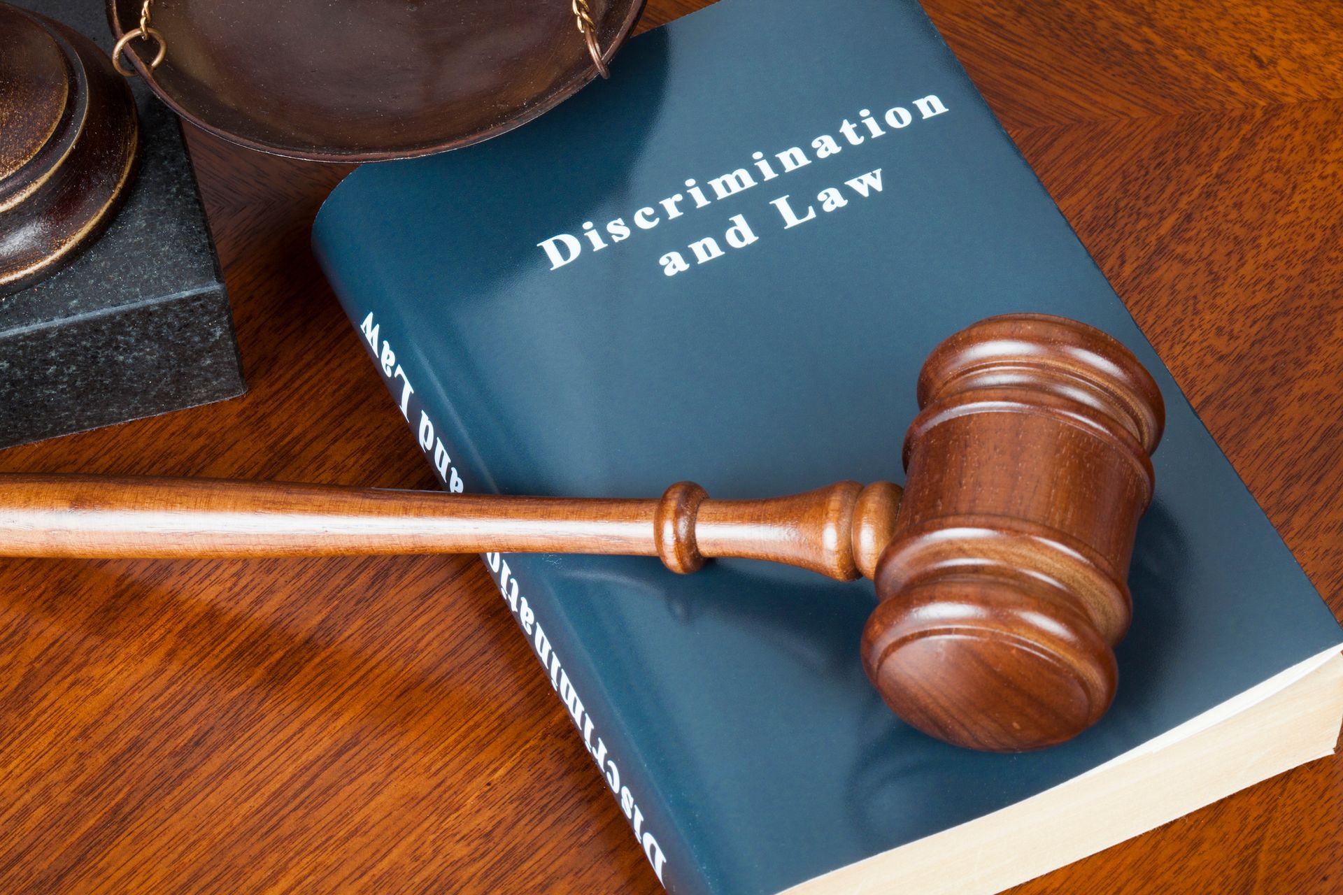 Wooden gavel resting on a discrimination law book, symbolizing justice and fairness. Wooden gavel resting on a discrimination law book, symbolizing justice and fairness.