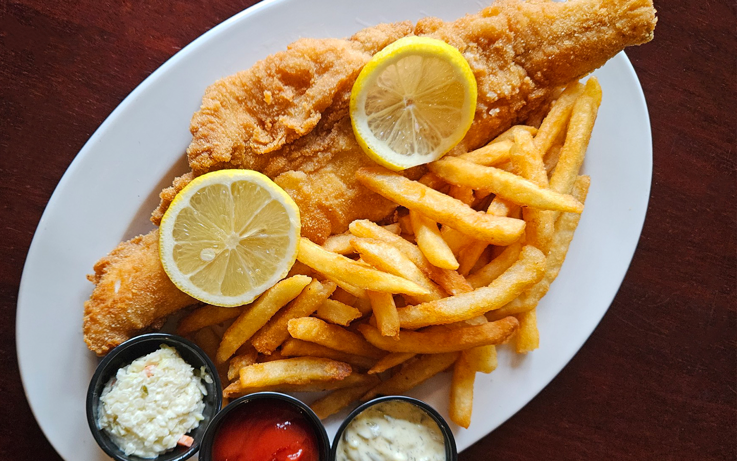 fish fry on platter with golden french fries, cole slaw, tartar sauce, and kethcup