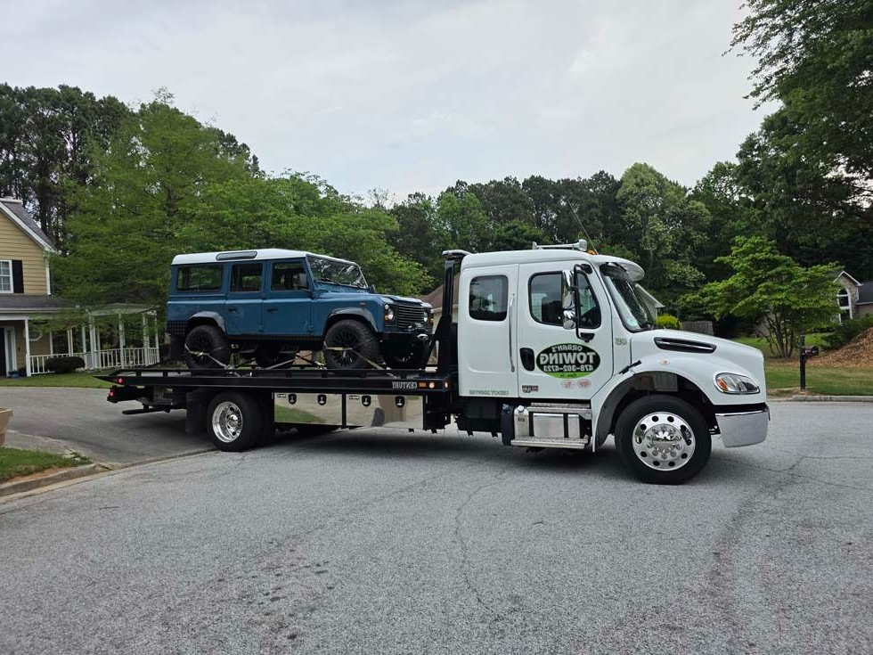 A damaged car loaded on a car hauler on a highway; sunny day.