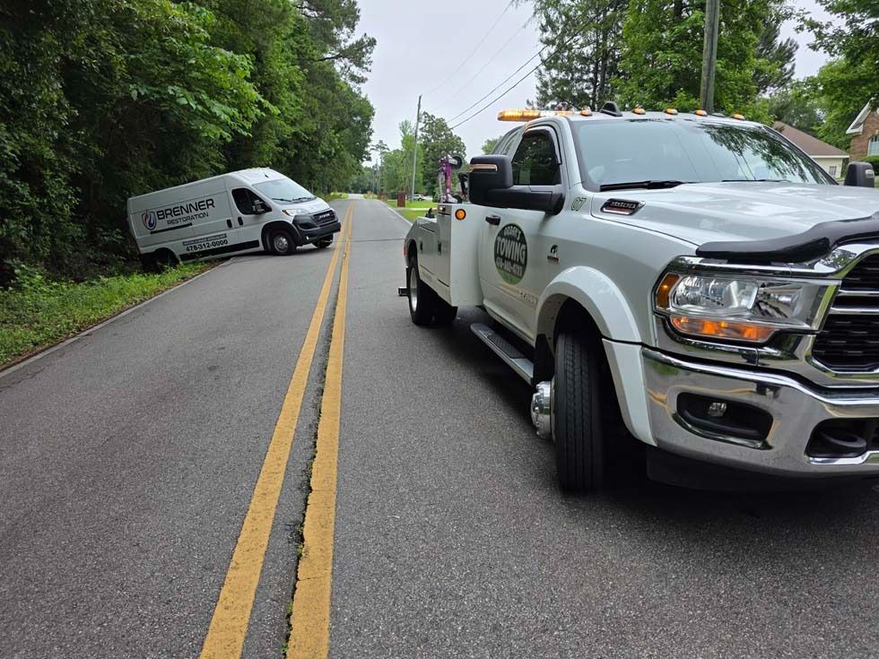 Tow truck near a road, next to a van that has crashed into the side of the road.