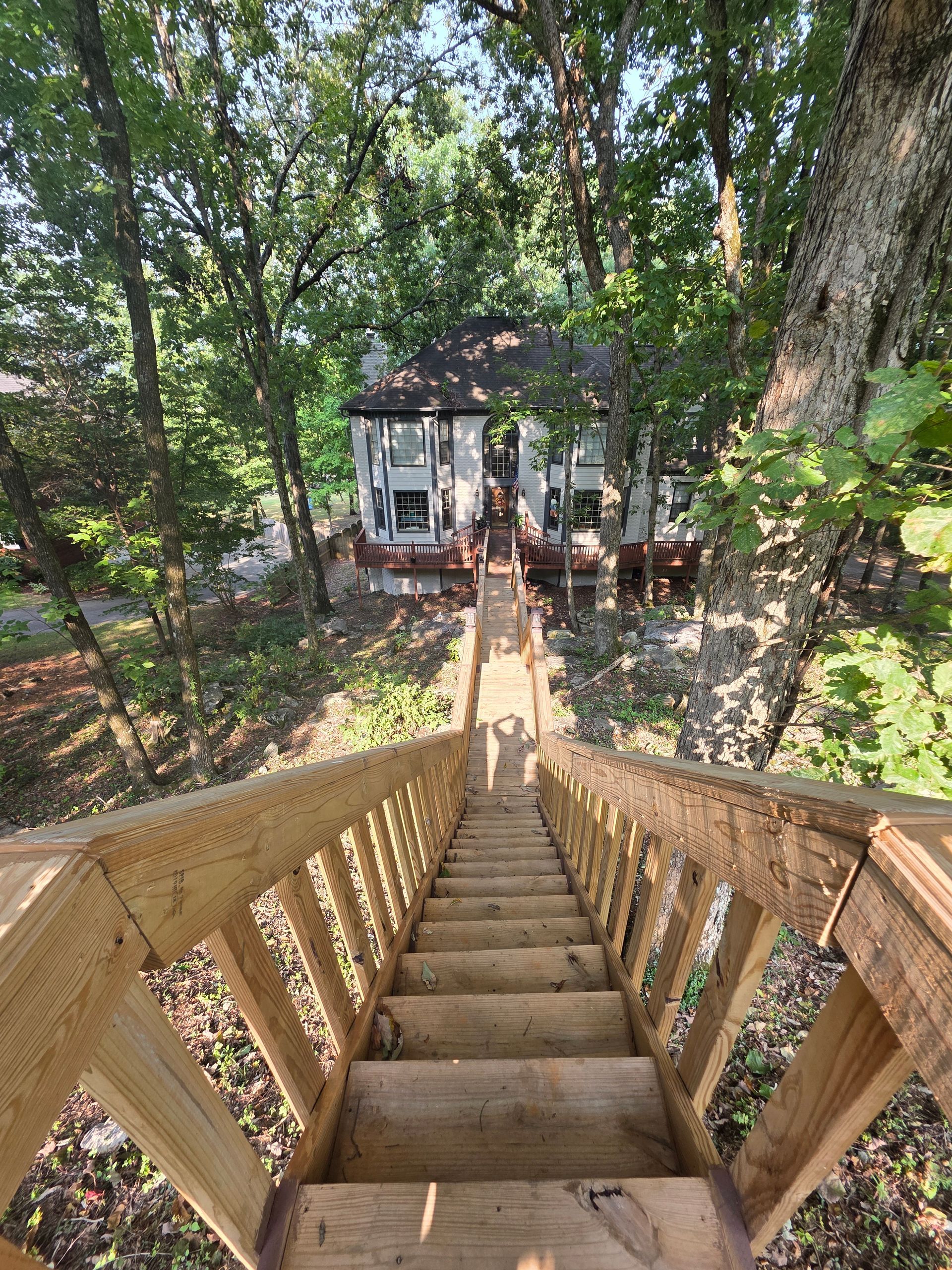 Wooden stairs leading up to a small house surrounded by trees.