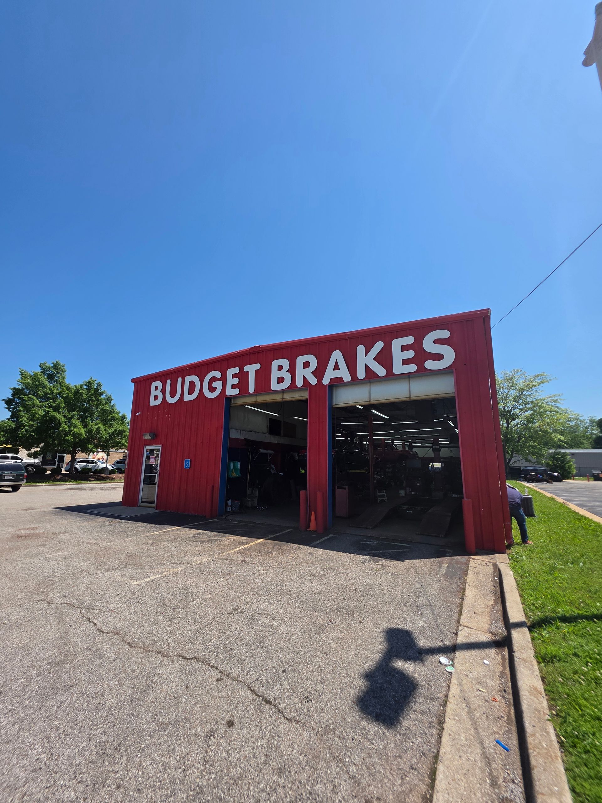 Red Budget Brakes building with open bays under blue sky.
