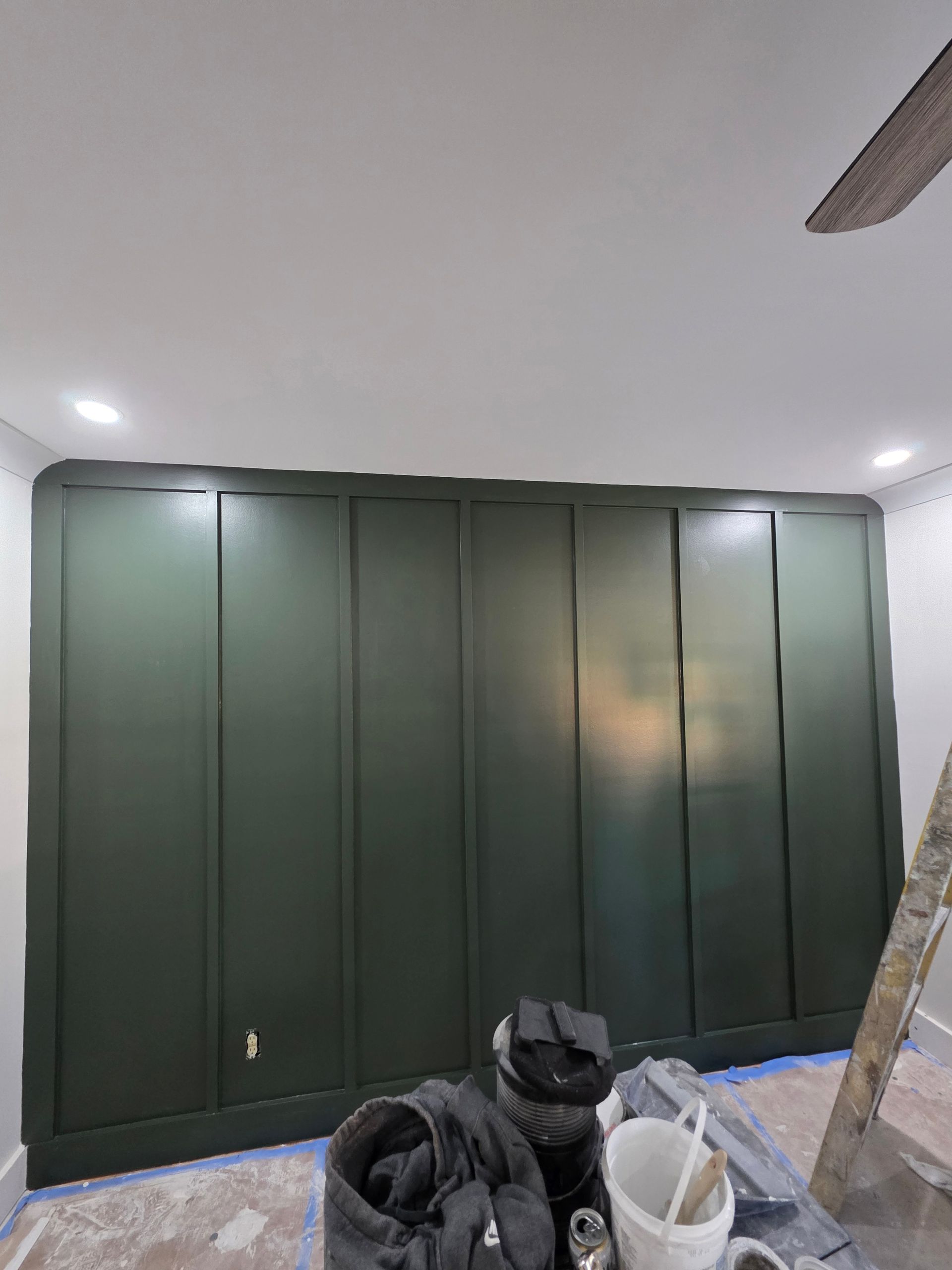 Green paneled accent wall in a room, with tools and equipment in front.
