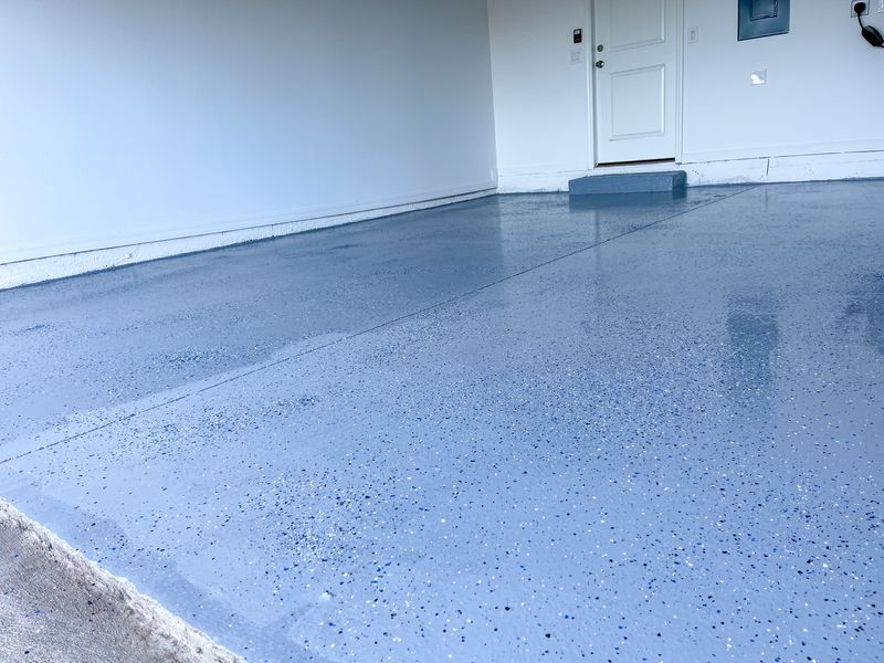 A shiny, blue speckled epoxy garage floor reflects light.