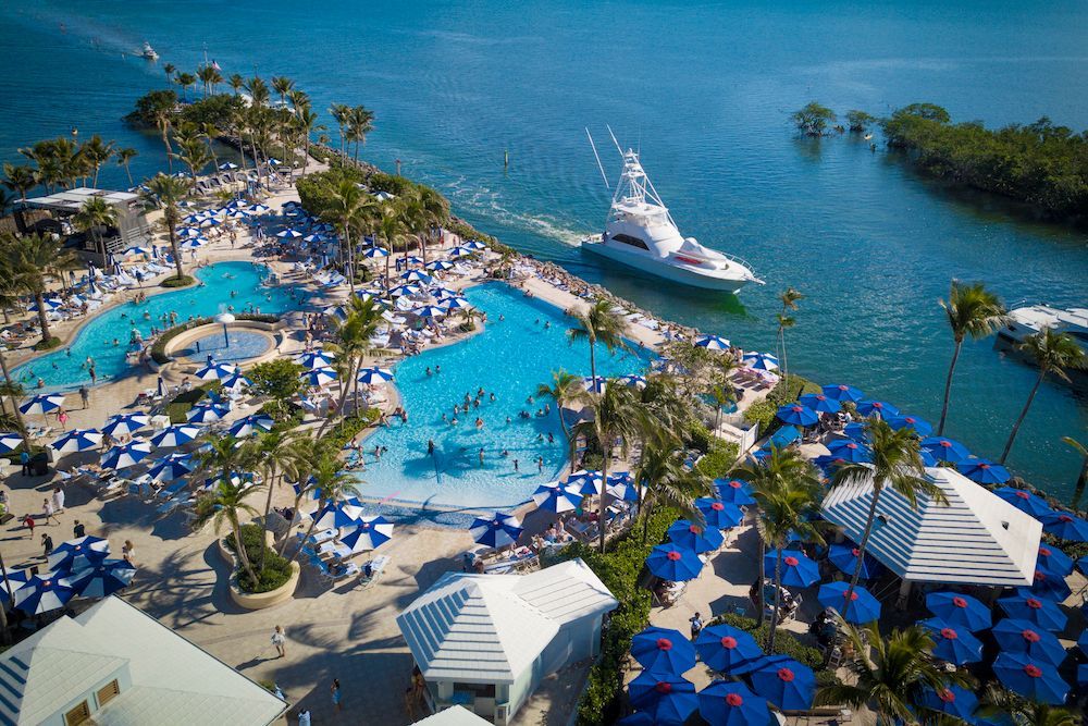 An aerial view of a resort with a large pool and a boat in the water.