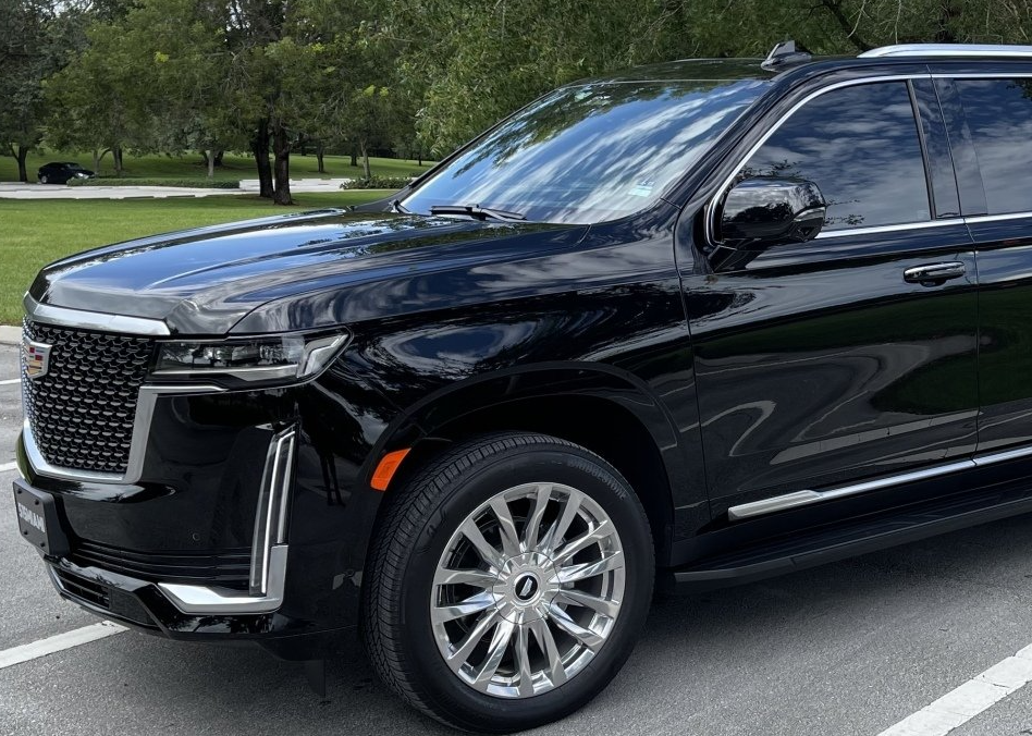 A black cadillac escalade is parked in a parking lot.
